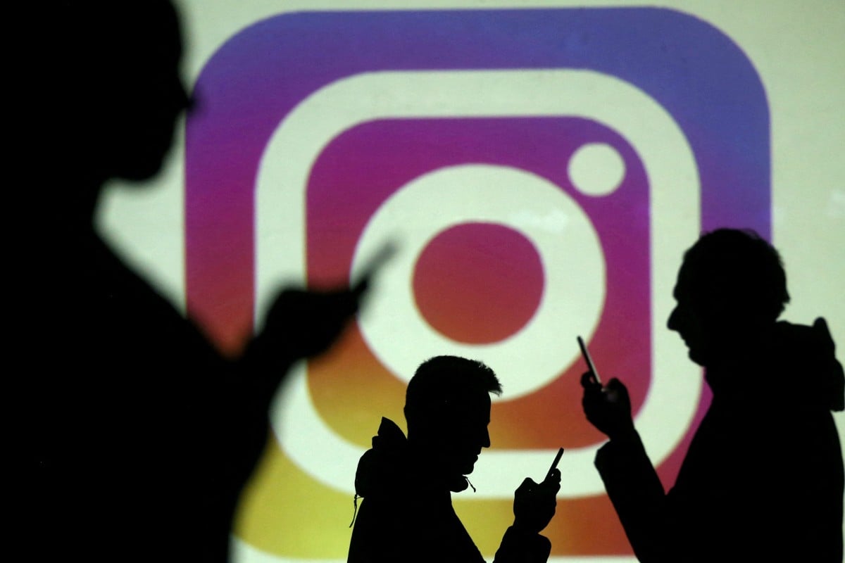 Silhouettes of smartphone users are seen next to a screen projection of the Instagram logo in this picture illustration.  Photo: Reuters